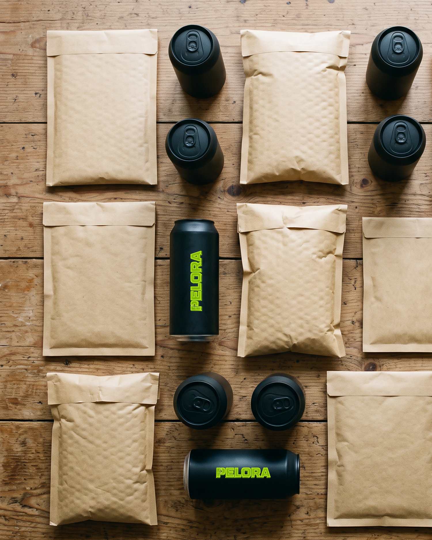 Plain kraft mailers and PELORA cans laid out in a grid on a wooden table, seen from above. Concept render by PELORA.
