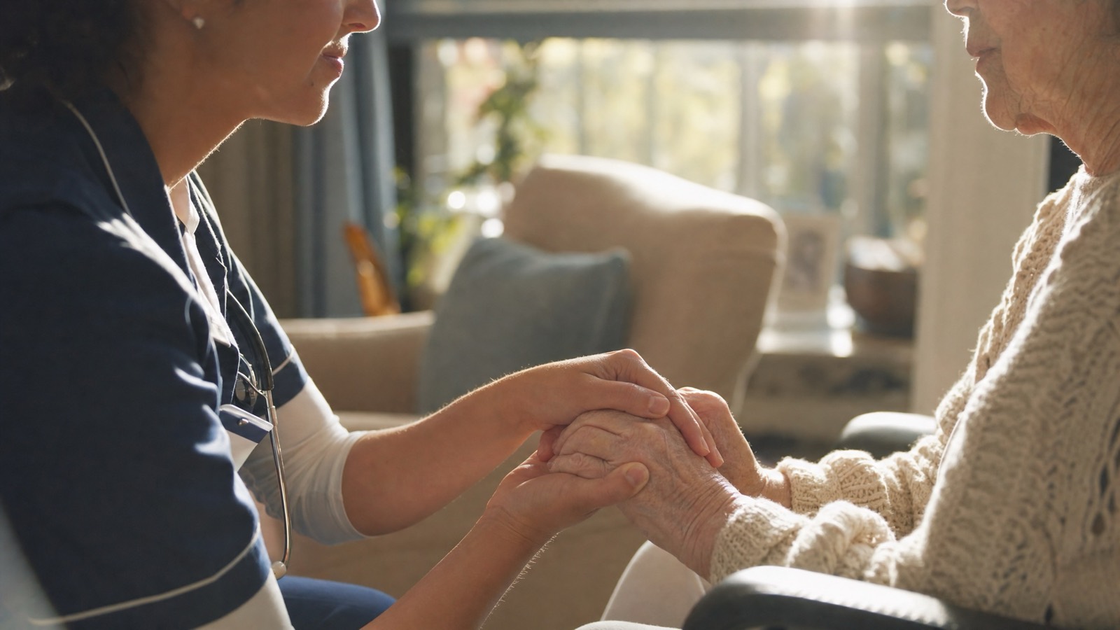 Nurse in profile holding a client's hands in a home setting, concept render by PELORA