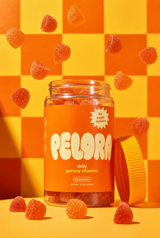 PELORA daily gummy vitamins jar with orange gummies falling around it on an orange checkerboard, in house packaging concept produced by PELORA Marketing